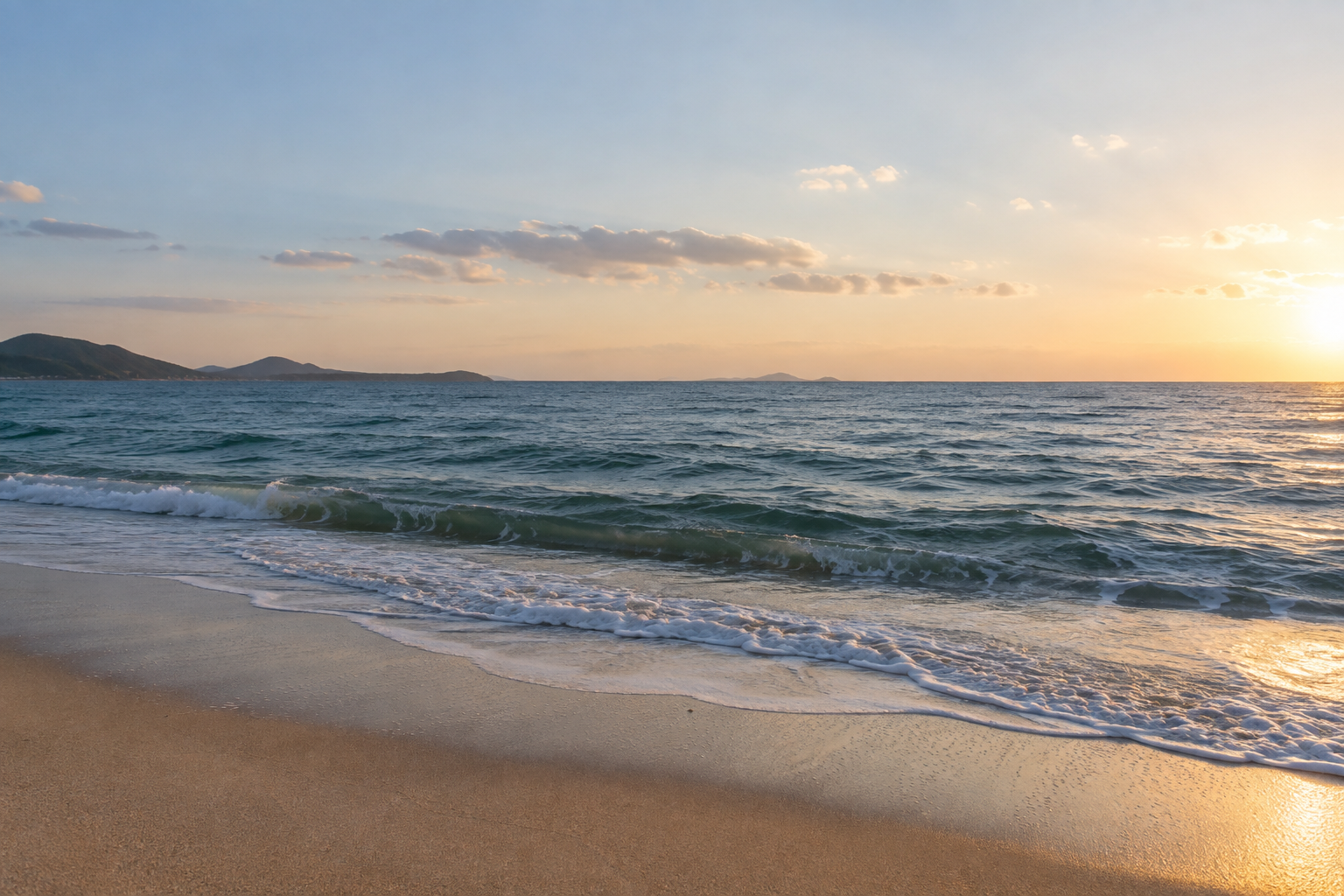 柔らかな夕日と、砂浜に寄せる穏やかな波